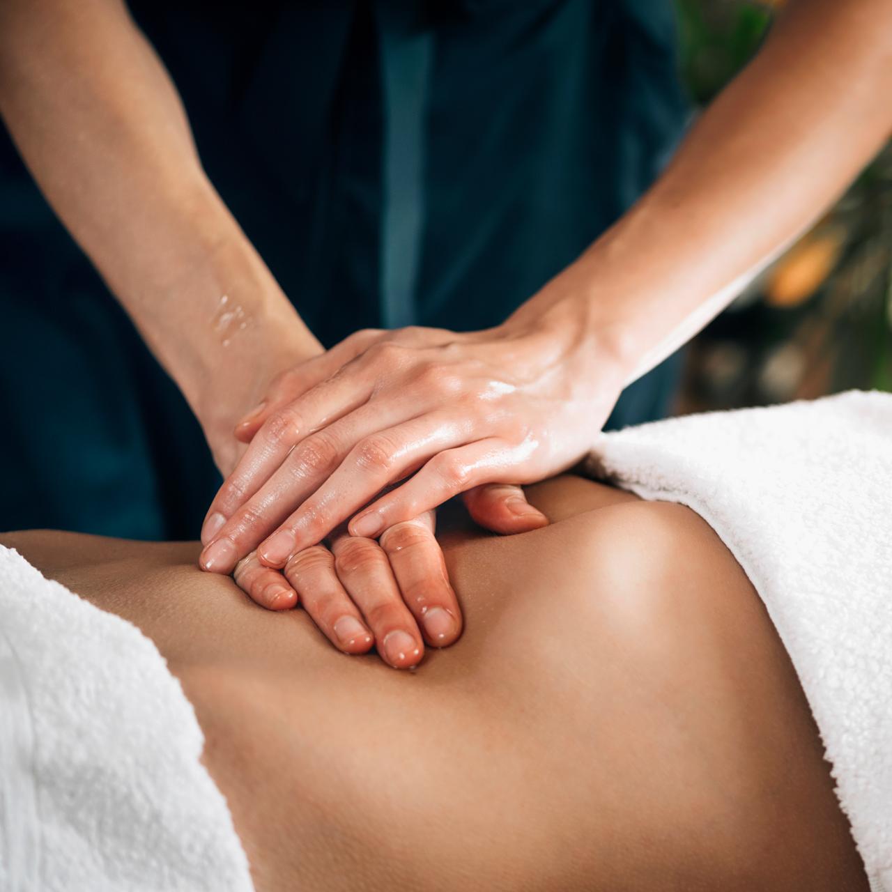 Massage manuel avec huile sur le dos d'une patiente allongée, dans une ambiance de soin apaisante